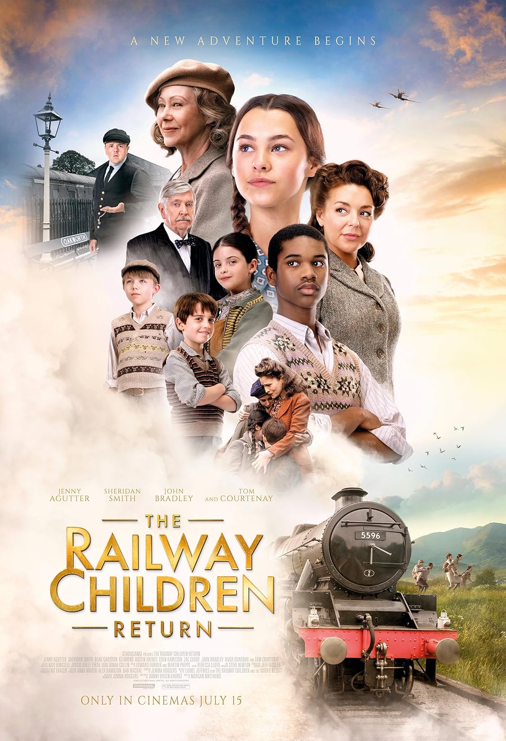 A movie poster for "The Railway Children Return" featuring a group of children and adults in period clothing layered against a soft sky, with a steam train emerging from mist in the foreground. The cast look upward or ahead, with planes flying overhead and rolling hills in the background.